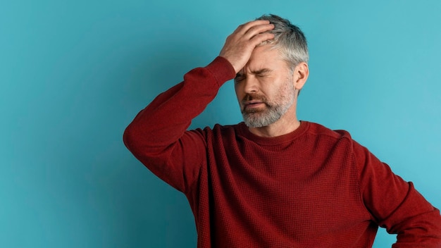 Homme barbu aux cheveux gris d'âge moyen touchant la tête