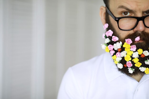 Un homme barbu avec une barbe décorée pour les vacances de printemps. Fleurs dans la barbe.