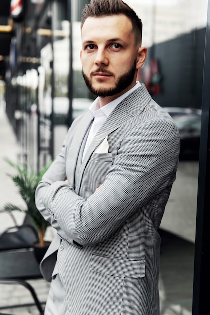 Un homme barbu avec une barbe rouge dans une chemise, un gilet et des lunettes.