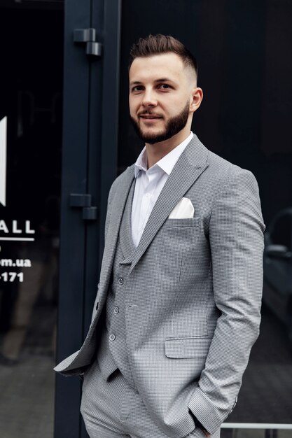 Un homme barbu avec une barbe rouge dans une chemise, un gilet et des lunettes.