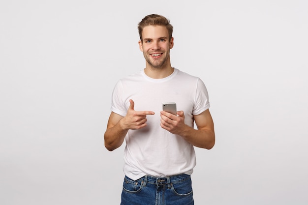 Homme barbu blond séduisant en T-shirt blanc à l'aide de smartphone
