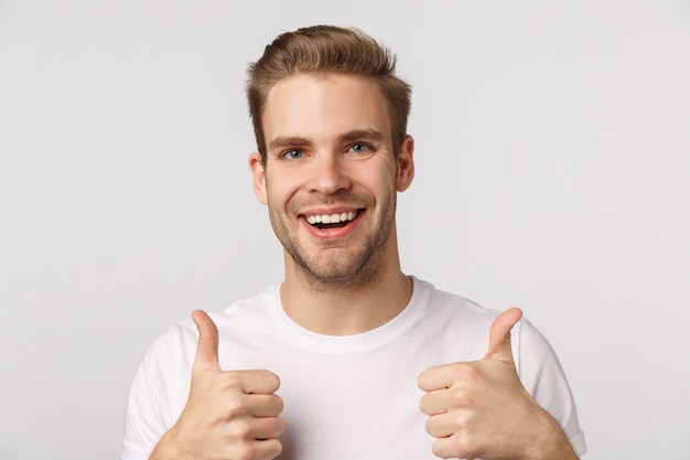 Homme barbu blond séduisant en T-shirt blanc donnant les pouces vers le haut