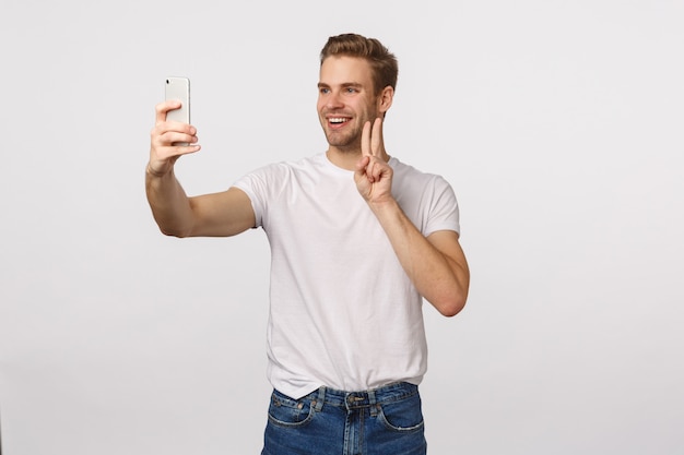 Homme barbu blond séduisant en T-shirt blanc prenant selfie