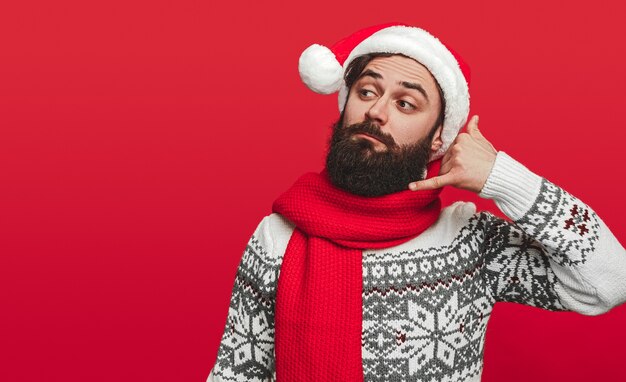 Homme barbu en bonnet de Noel tenant un téléphone imaginaire