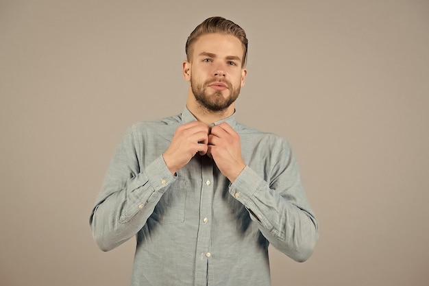 Homme barbu bouton chemise bleue Homme avec barbe sur la peau du visage non rasé Mannequin en tenue décontractée sur fond gris Concept de style ou de tendance et de vogue Salon de soins de la peau et de coiffure