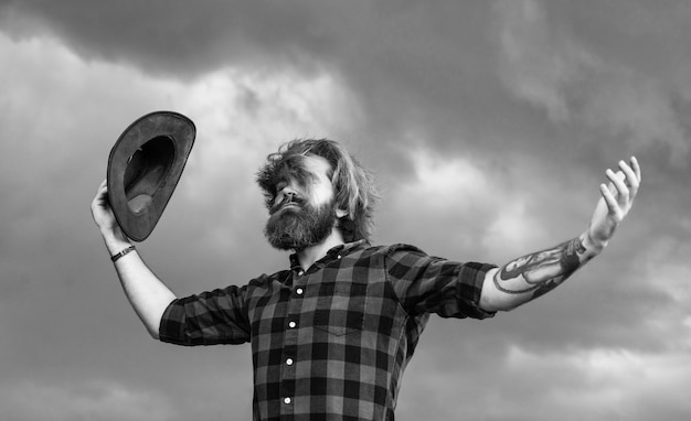 Un homme barbu brutal tient la liberté du chapeau de cow-boy