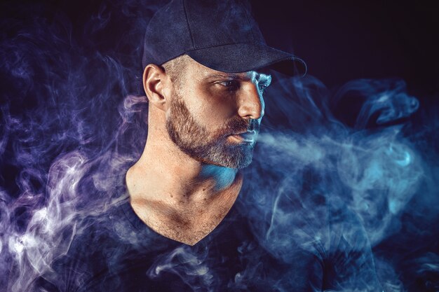 Homme barbu brutal vaping et libère un nuage de vapeur