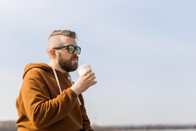 Homme barbu buvant un fond de ciel secoué boissons à emporter et gen z ou concept de jeunesse du millénaire