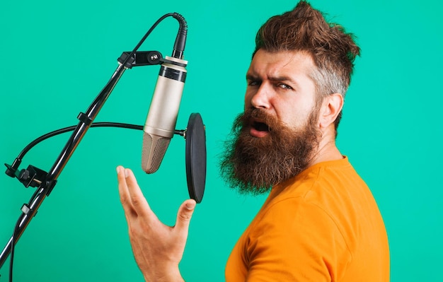 Un homme barbu chante dans un studio de microphone à condensateur enregistre la production musicale d'un chanteur professionnel