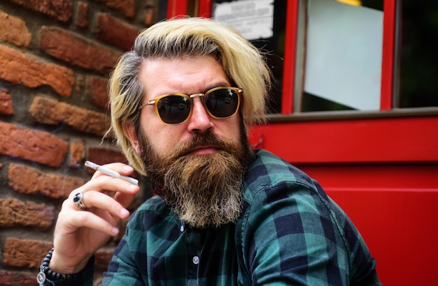 Homme barbu avec cigarette agrandi portrait de mec fumeur beau fumeur mâle à lunettes de soleil