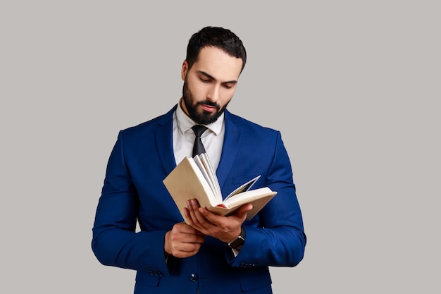 Homme barbu concentré lisant un livre appréciant la lecture debout absorbé par une intrigue passionnante