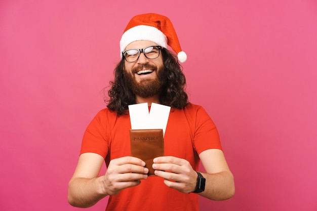 L'homme barbu cool est heureux et prêt avec un passeport pour voyager à Noël