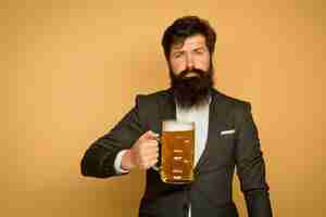Photo homme barbu en costume noir avec un verre de bière homme élégant heureux buvant de la bière pubs et bars be...