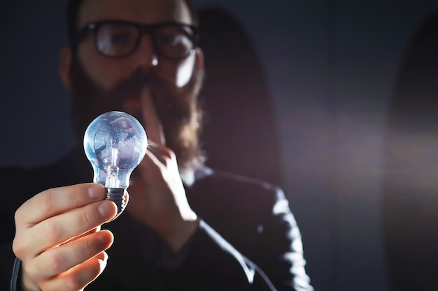 Un homme barbu en costume tient un objet dans sa main. Concept de temps et d'idées. Aspiration et développement.