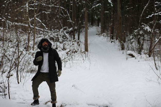 Homme barbu dans les bois d'hiver. Séduisante jeune homme heureux avec barbe marche dans le parc.