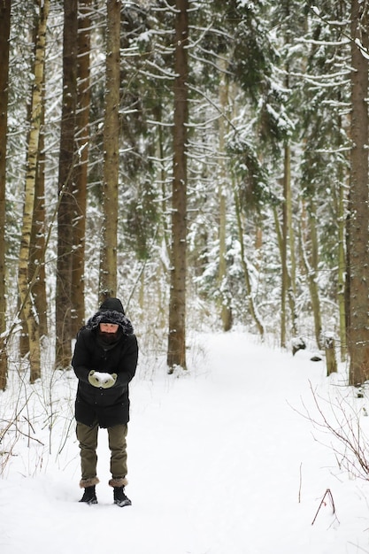 Homme barbu dans les bois d'hiver. Séduisante jeune homme heureux avec barbe marche dans le parc.