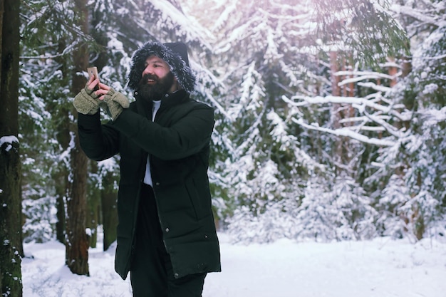 Homme barbu dans les bois d'hiver. Séduisante jeune homme heureux avec barbe marche dans le parc.