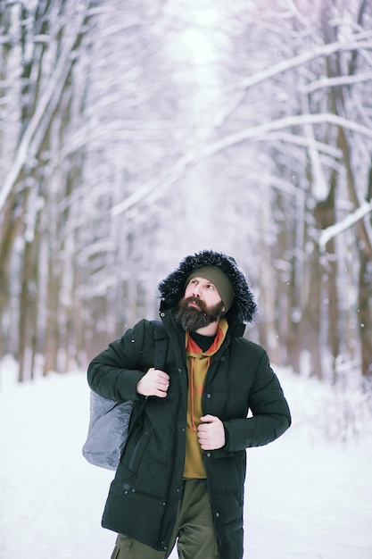 Homme barbu dans les bois d'hiver. Séduisante jeune homme heureux avec barbe marche dans le parc.