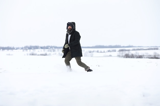 Homme barbu dans les bois d'hiver. Séduisante jeune homme heureux avec barbe marche dans le parc.