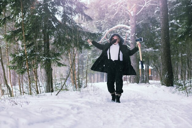 Homme barbu dans les bois d'hiver. Séduisante jeune homme heureux avec barbe marche dans le parc.