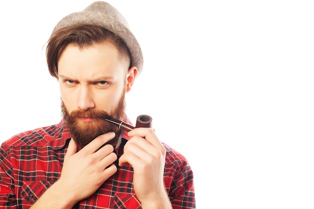 Homme barbu dans un chapeau fumant une pipe. Isolé sur blanc.