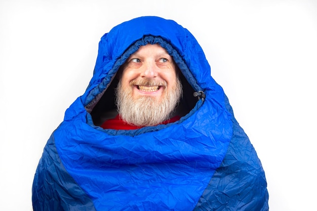 Photo homme barbu dans un sac de couchage sur un fond jaune équipement de loisirs dans le tourisme et les voyages