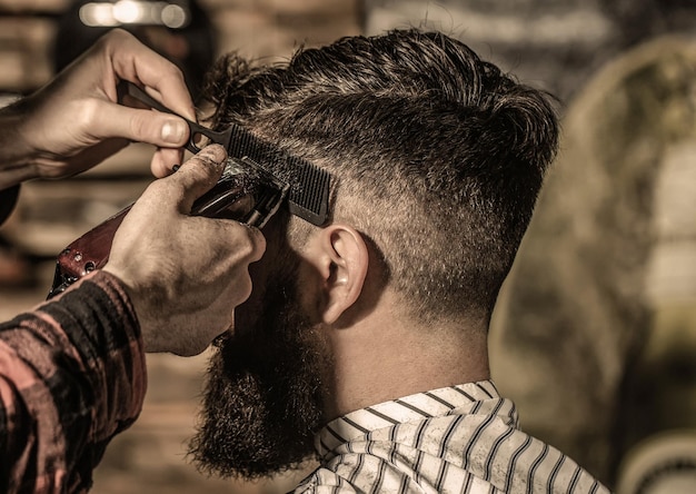 Homme barbu dans un salon de coiffure Concept de coupe de cheveux Homme visitant un coiffeur dans un salon de coiffure