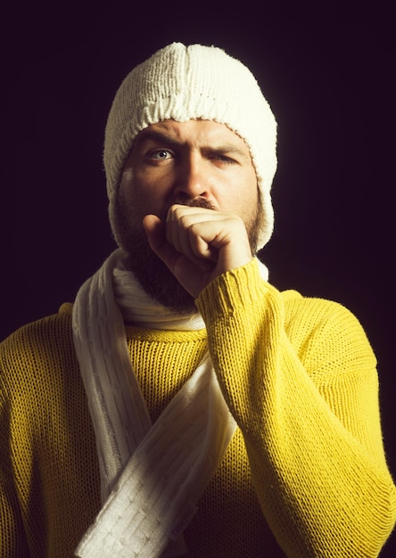 L'homme barbu en écharpe est malade d'un rhume ou d'une pneumonie. Souffrant du virus de la grippe. L'homme toussa dans son poing. Vêtements de style hiver.