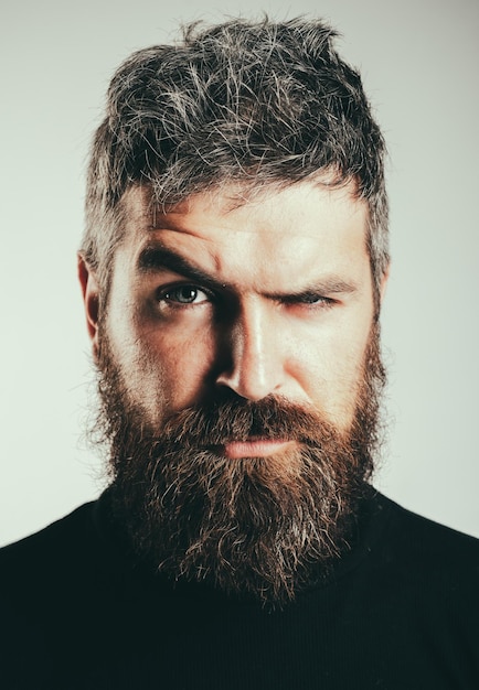 Homme barbu élégant sérieux Beau jeune homme isolé Portrait en gros plan d'un homme barbu chaud sévère avec une coiffure élégante Isolé sur fond gris Concept de personnes Lifestyle Homme barbu