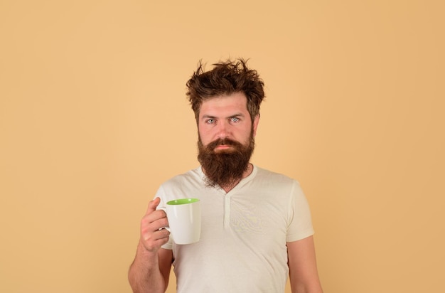 Un homme barbu éveillé avec une tasse de café un gars fatigué tient un homme de café tient une tasse avec du thé chaud le matin