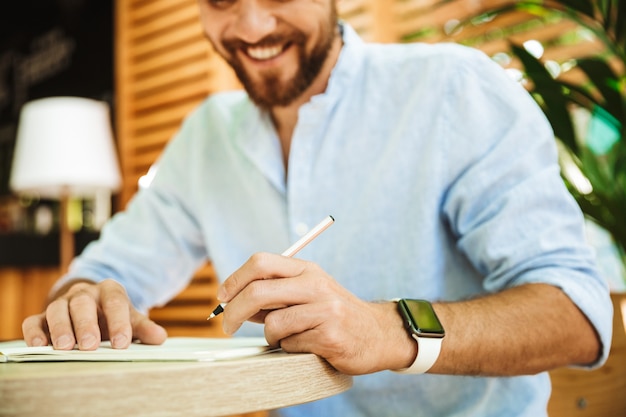 Homme barbu à l'extérieur, écrire des notes