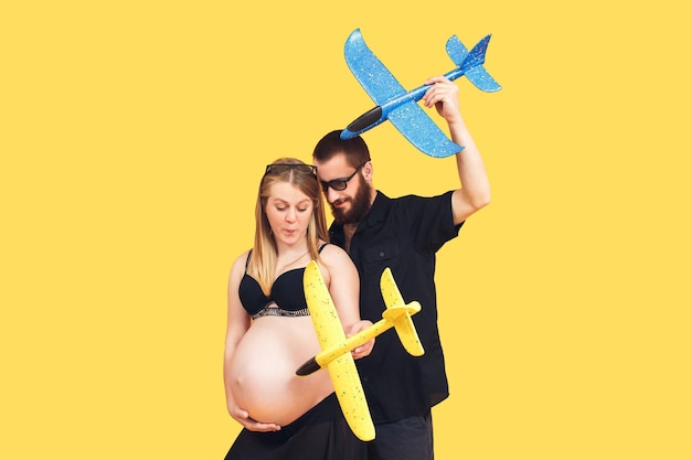 Un homme barbu et une fille enceinte jouent avec des avions jaunes et bleus Le concept d'une protection pacifique du ciel contre les attaques aériennes