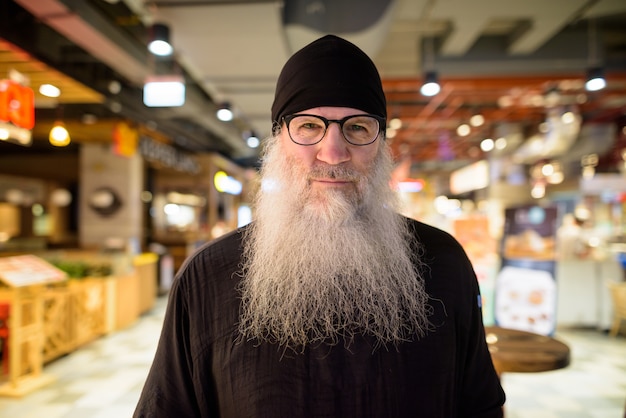 Homme barbu hipster mature avec des lunettes à l'intérieur du centre commercial