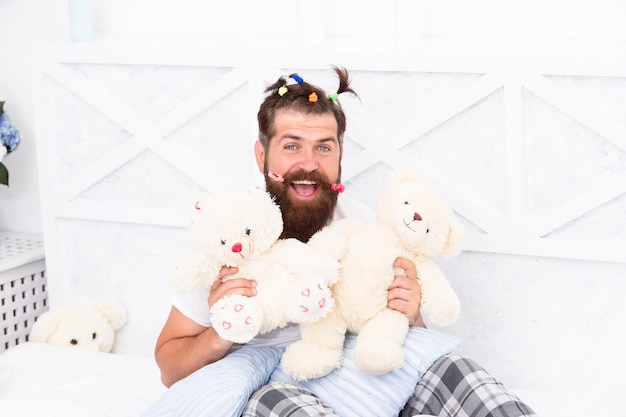 Homme barbu jouer avec un jouet ours papa heureux relaxant chambre père avec une coiffure drôle hipster bizarre se détendre au lit rester au lit toute la journée pour se détendre à la maison paternité heureuse inspiré pour jouer