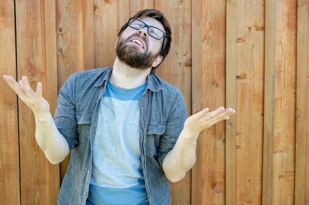 Un homme barbu lève les paumes et la tête et fait un gémissement Émotions de désespoir et de problèmes