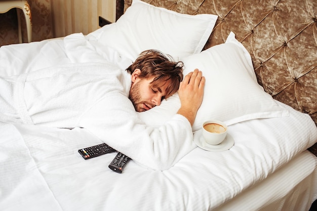 Homme barbu sur lit avec télécommande