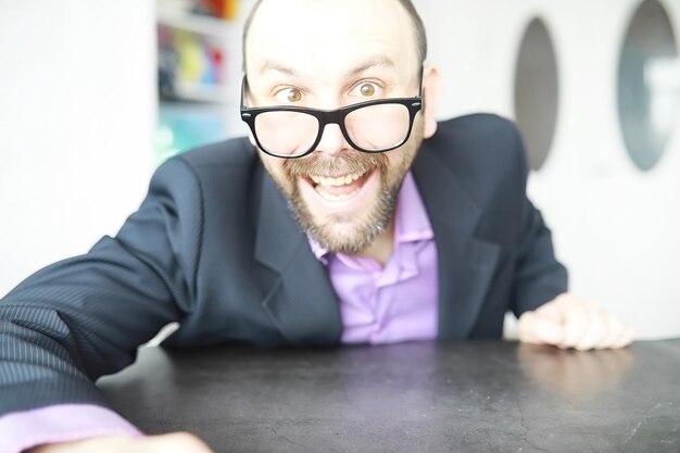 Un homme barbu louche regarde dans le cadre. Maladie des yeux. Le concept d'un spécialiste inexpérimenté. Voisin espion.