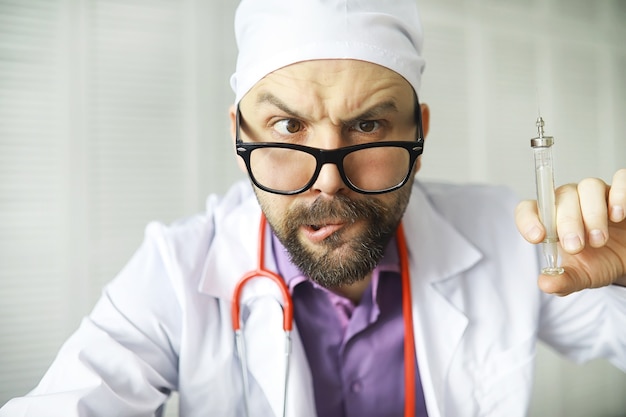 Un homme barbu louche regarde dans le cadre. Maladie des yeux. Le concept d'un spécialiste médical fou. Docteur voisin.