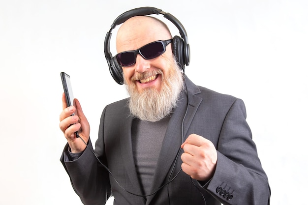 Photo un homme barbu avec des lunettes de soleil et des écouteurs écoute de la musique à l'aide d'un lecteur sur un fond blanc