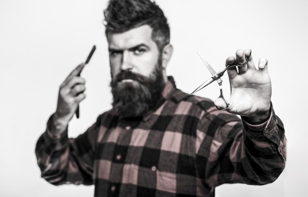 Homme barbu, mâle barbu. Portrait de barbe d'homme élégant. Ciseaux de coiffeur et rasoir droit, salon de coiffure. Salon de coiffure vintage, rasage. Noir et blanc