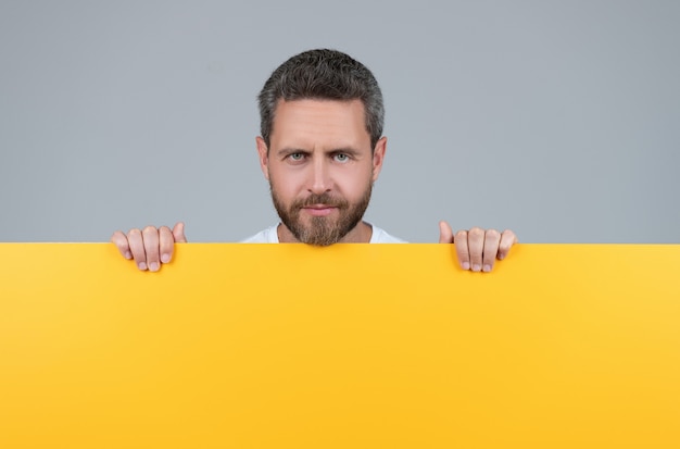 Homme barbu mature derrière du papier jaune avec copie scape, publicité.