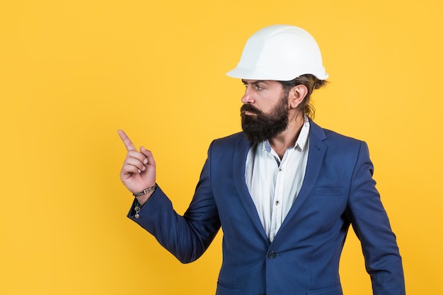 Homme barbu mature ou homme d'affaires en costume et casque, architecture.