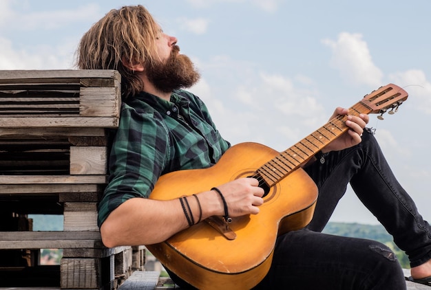 Homme barbu mature à la mode décontracté jouant de la guitare se détendre