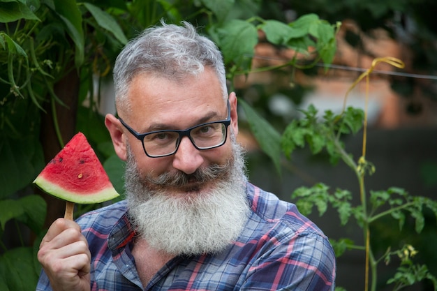 Homme barbu mature avec une tranche de pastèque