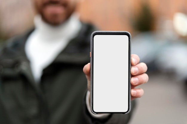 Un homme barbu montre un smartphone avec un écran tactile Nettoyer l'espace de l'écran pour les publicités