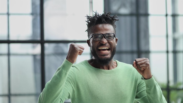 Homme barbu oyful dans des vêtements formels serrant ses poings avec bonheur