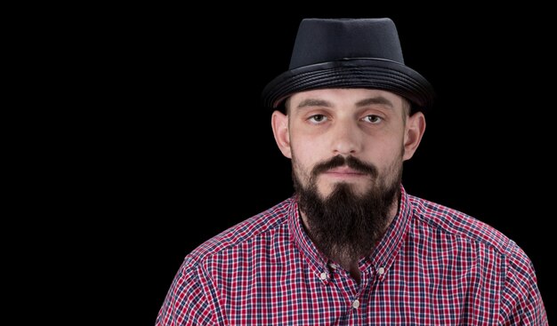 Photo homme barbu pensif vêtu d'une chemise et d'un chapeau en molleton posant sur fond noir