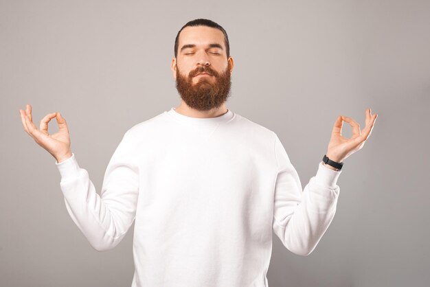 L'homme barbu positif est debout et tient les mains dans un geste zen