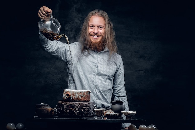 Un homme barbu positif verse de l'eau chaude lors d'une cérémonie du thé.