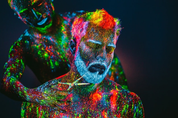 Homme barbu avec de la poudre ultraviolette dans un salon de coiffure